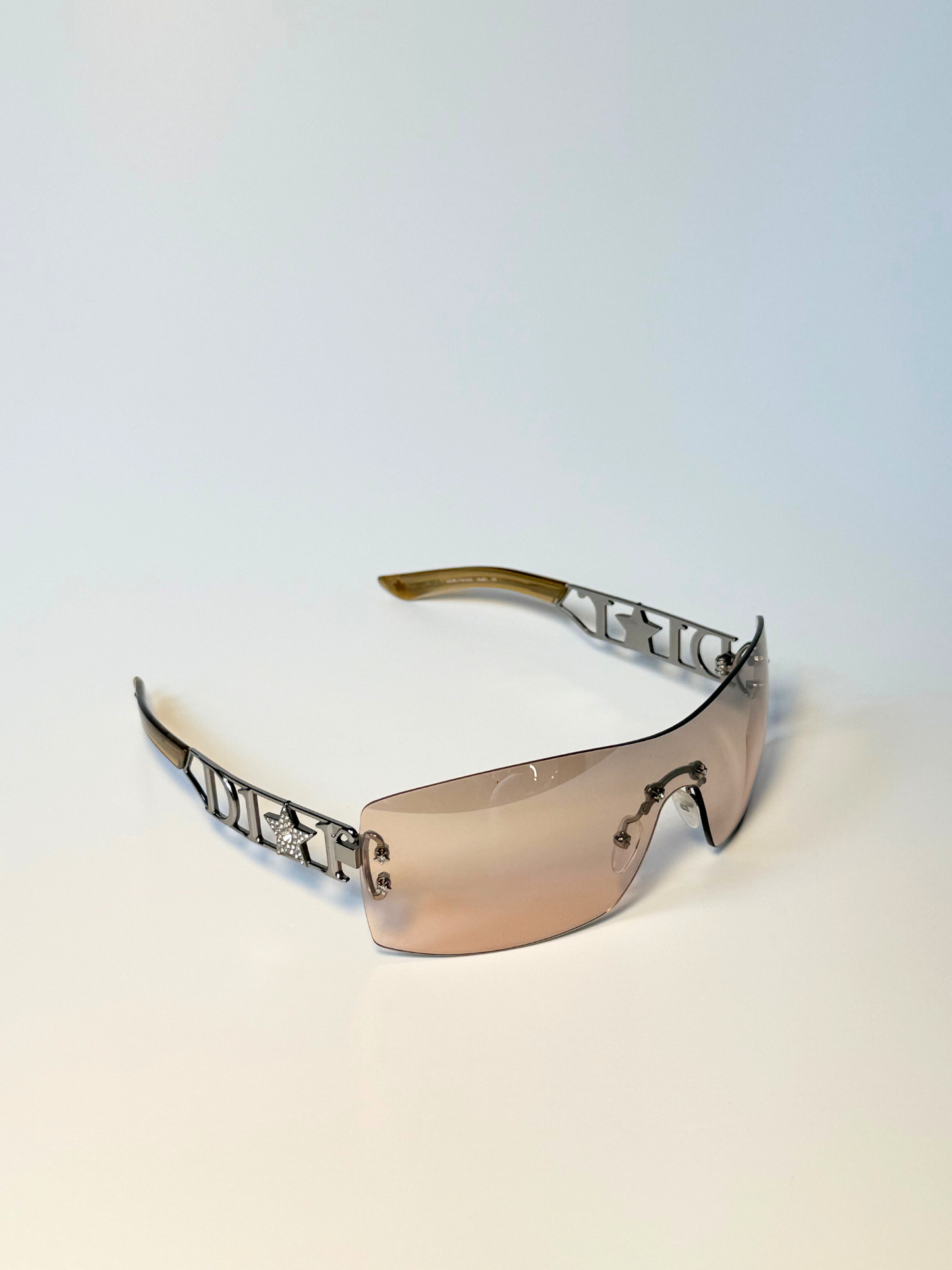 Close-up of Dior Diorlywood sunglasses showcasing engraved logo and brown gradient lenses