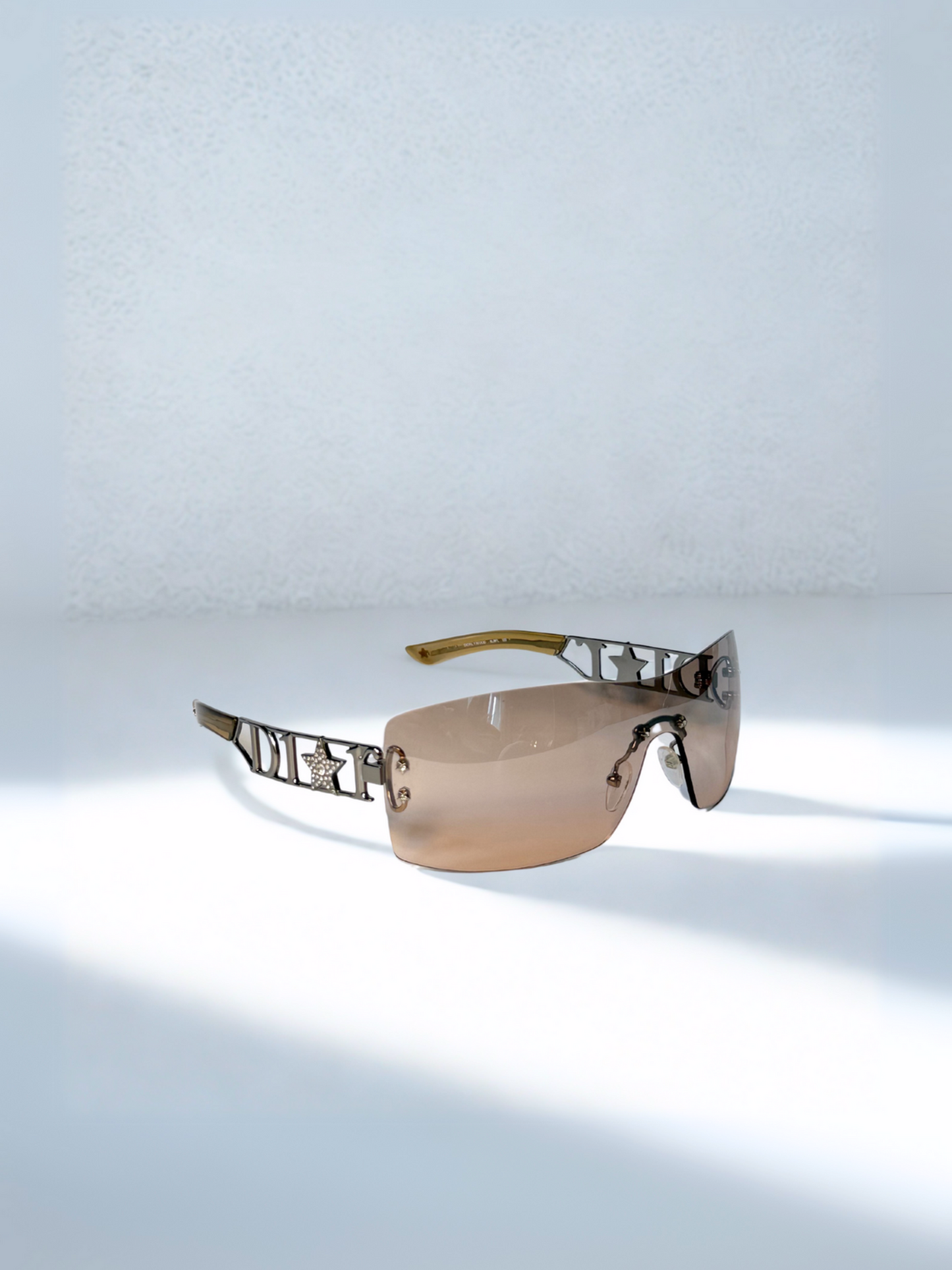 Close-up of Dior Diorlywood sunglasses showcasing engraved logo and brown gradient lenses